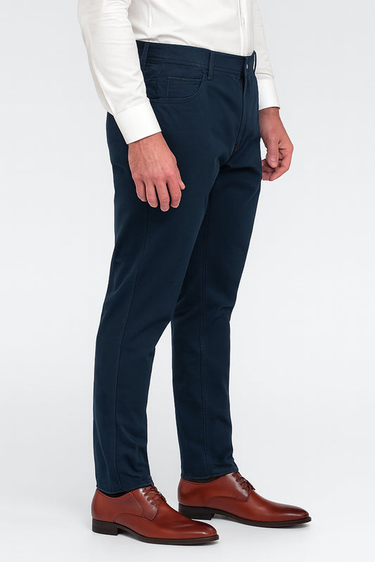 Person wearing navy pants and brown shoes on a white background