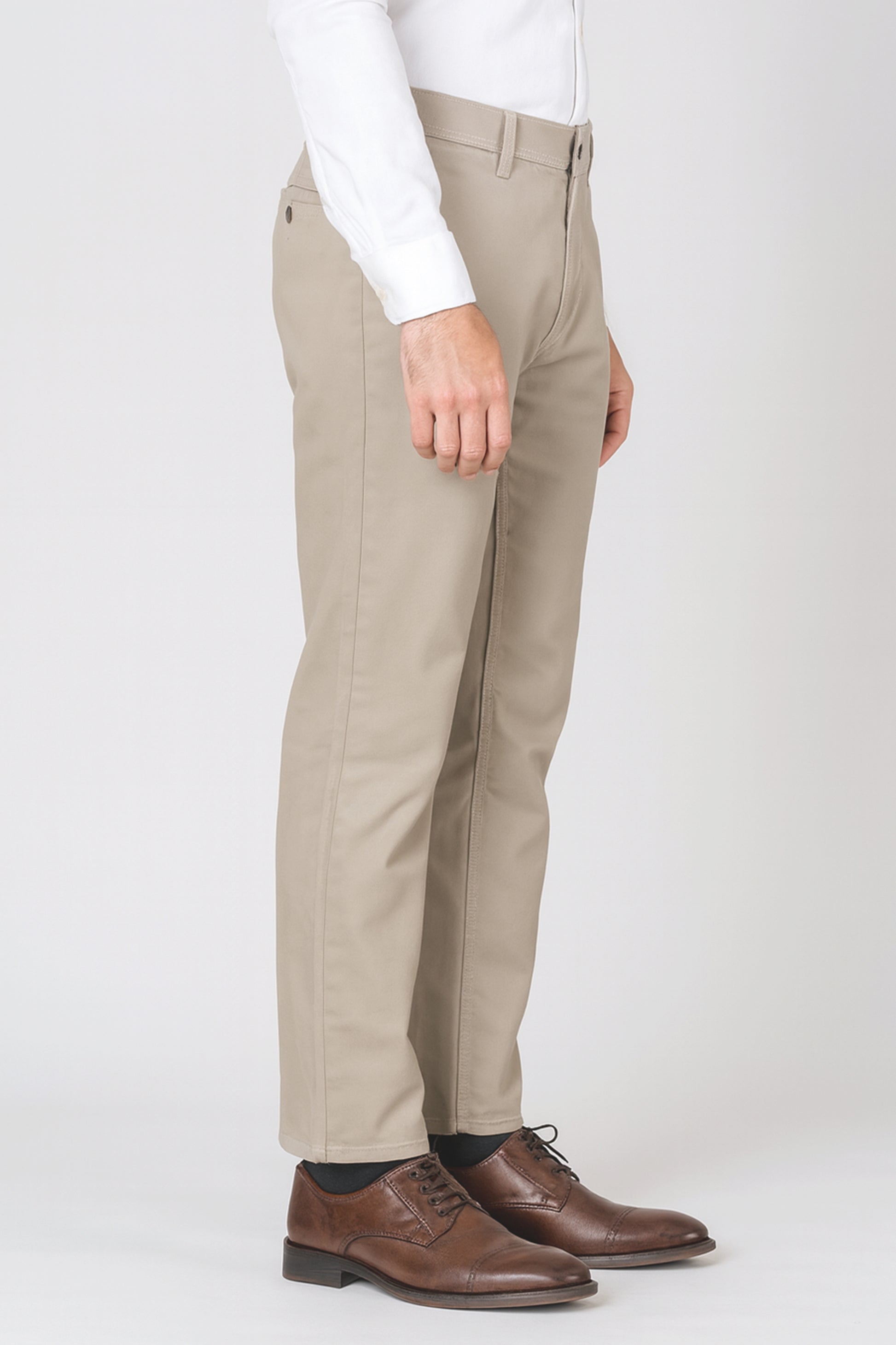 Beige pants worn with a white shirt and brown shoes on a white background