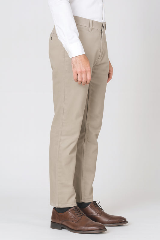 Beige pants worn with a white shirt and brown shoes on a white background