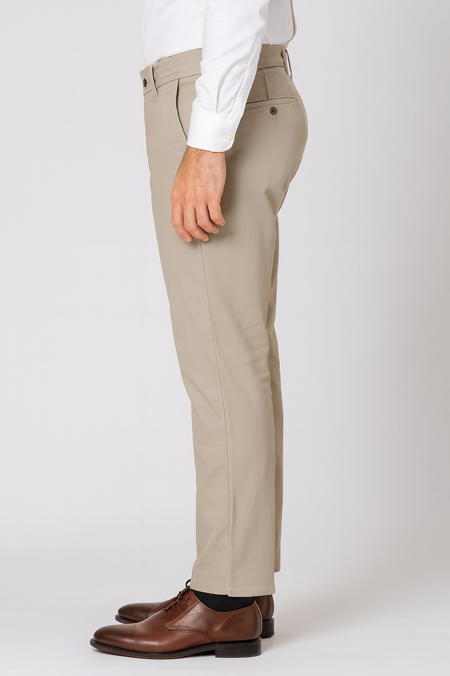 Beige pants worn with a white shirt and brown shoes on a white background