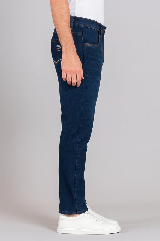 Person wearing dark blue jeans and white sneakers on a gray background