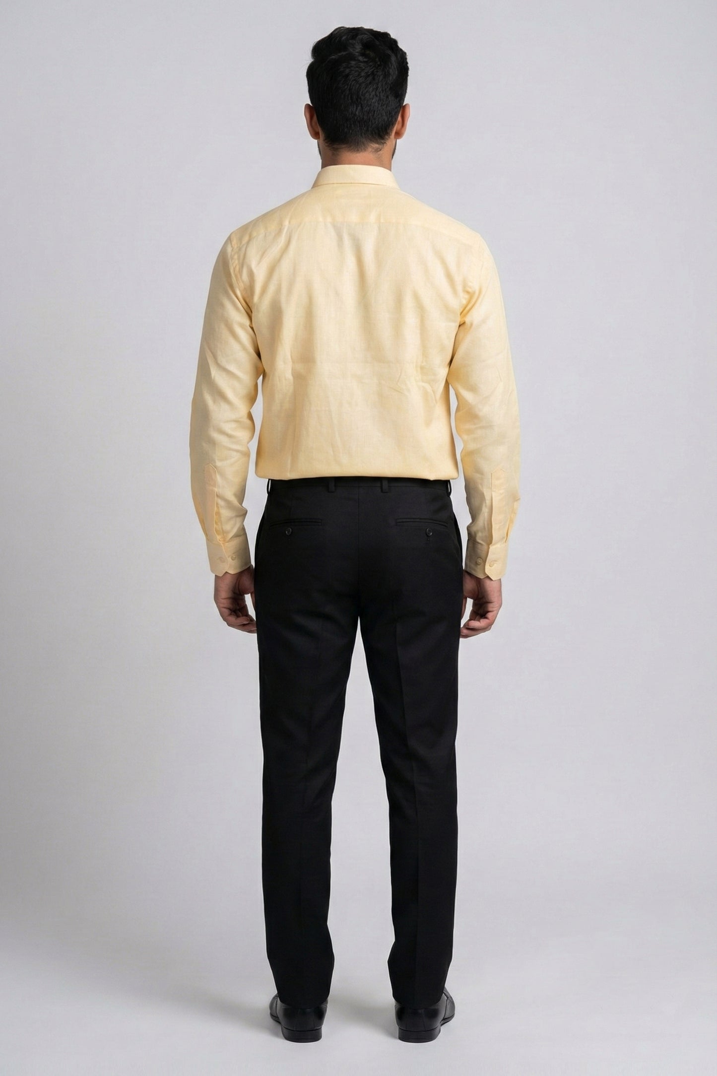 Man wearing a yellow shirt and black pants on a gray background