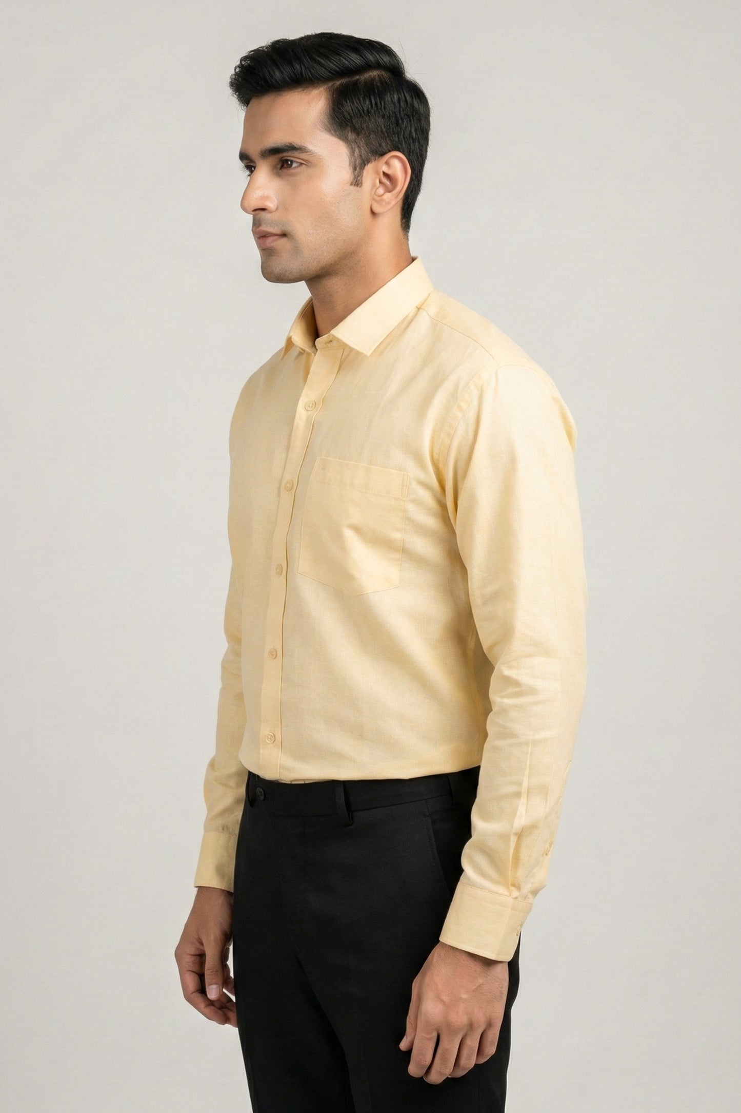 Man wearing a light yellow shirt and black pants on a gray background