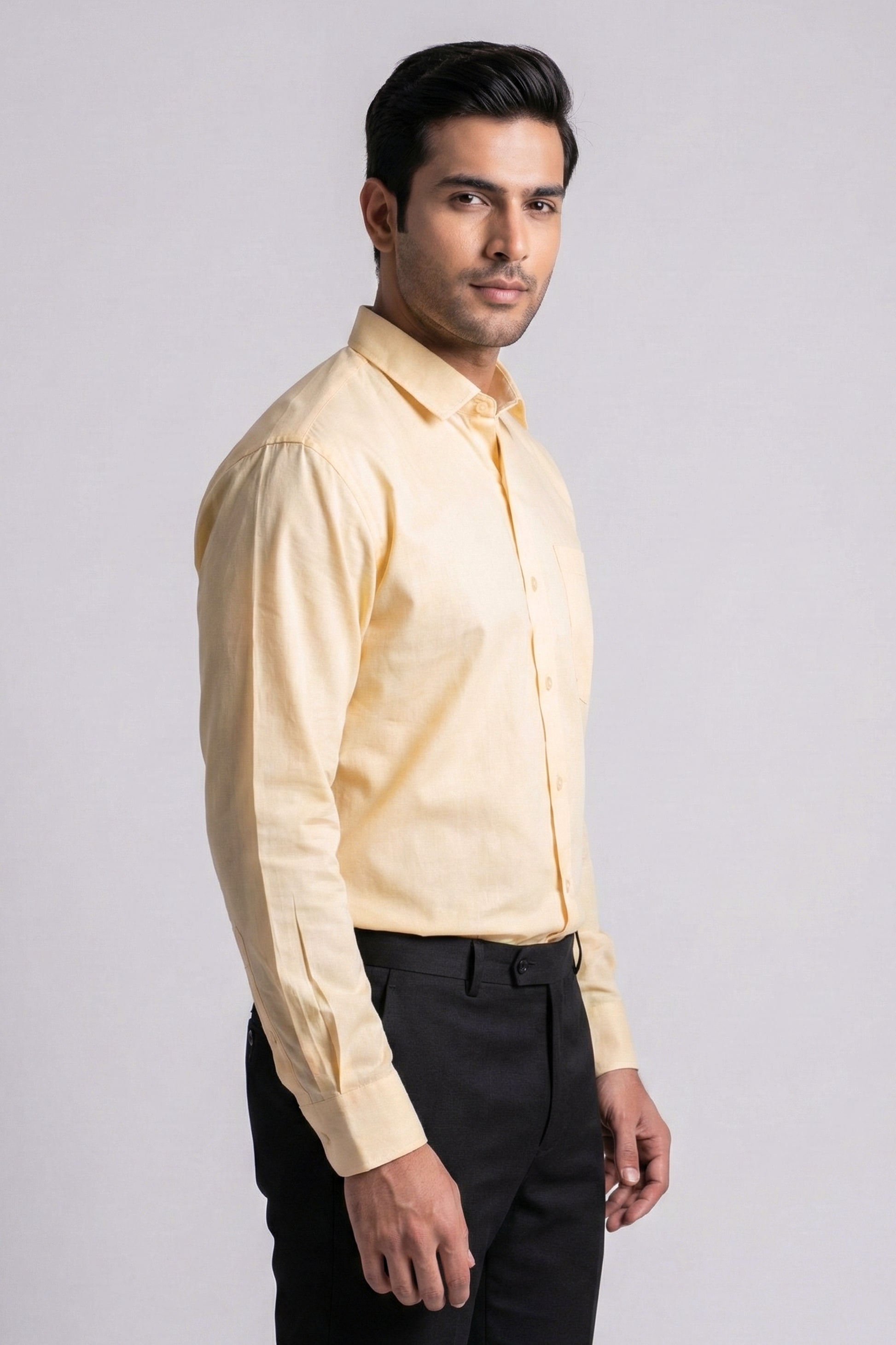 Man wearing a light yellow shirt and black pants on a gray background