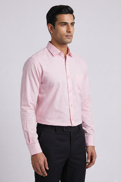 Man wearing a light pink shirt and black pants on a gray background