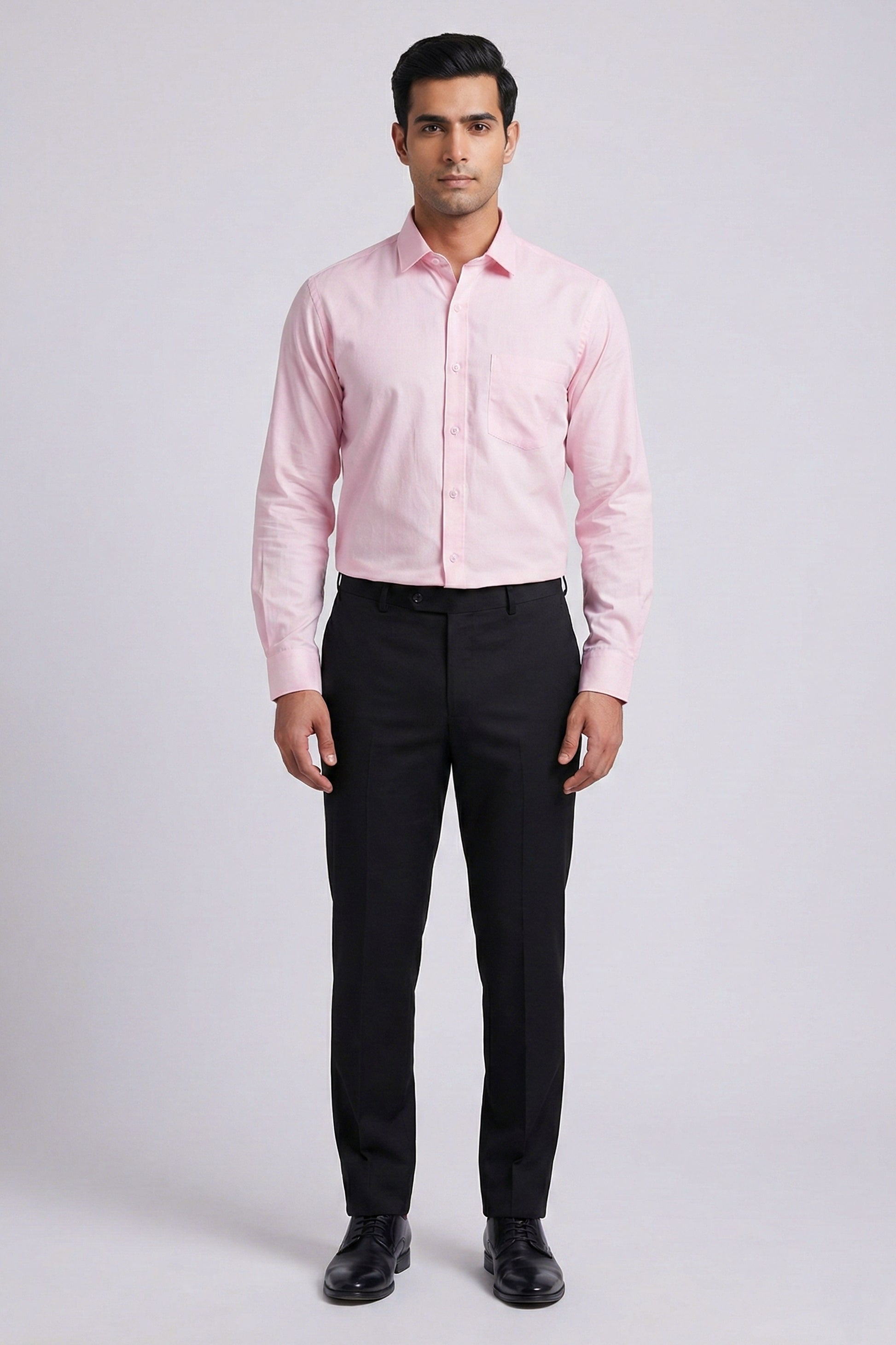 Man wearing a pink dress shirt and black pants on a white background