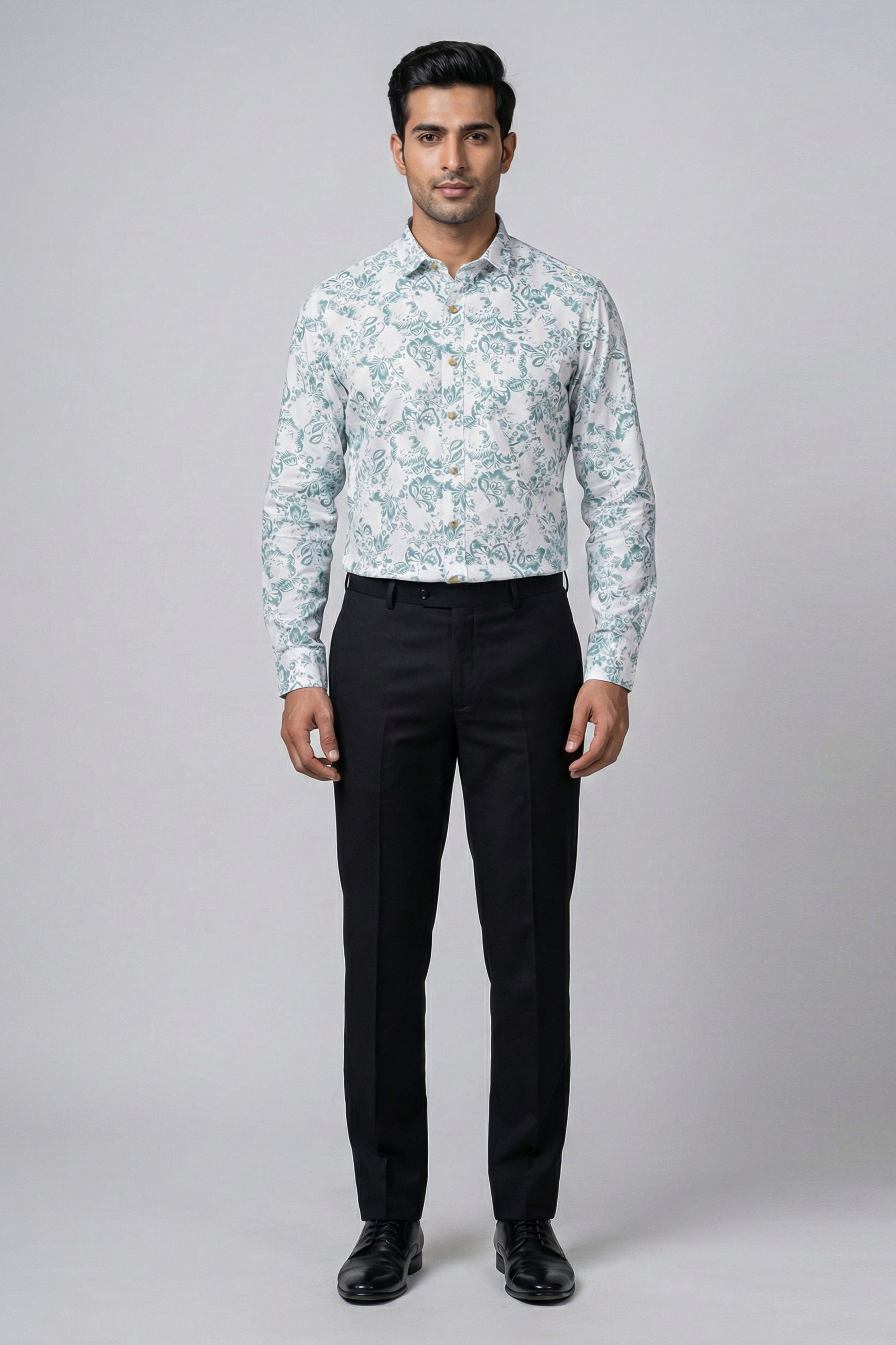 Man wearing a light blue floral shirt and black pants on a gray background