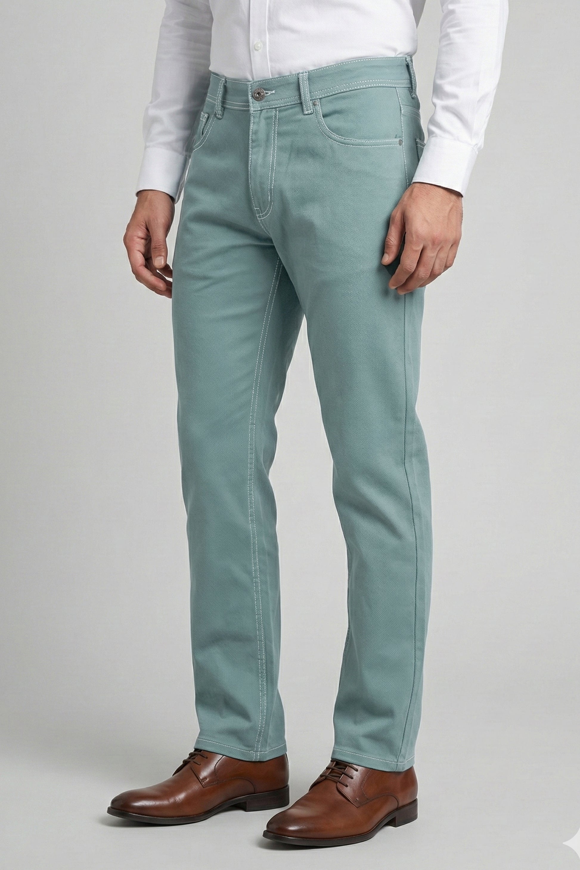 Person wearing light blue jeans and brown shoes on a plain background