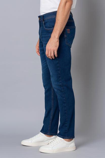 Person wearing blue jeans and white sneakers on a gray background