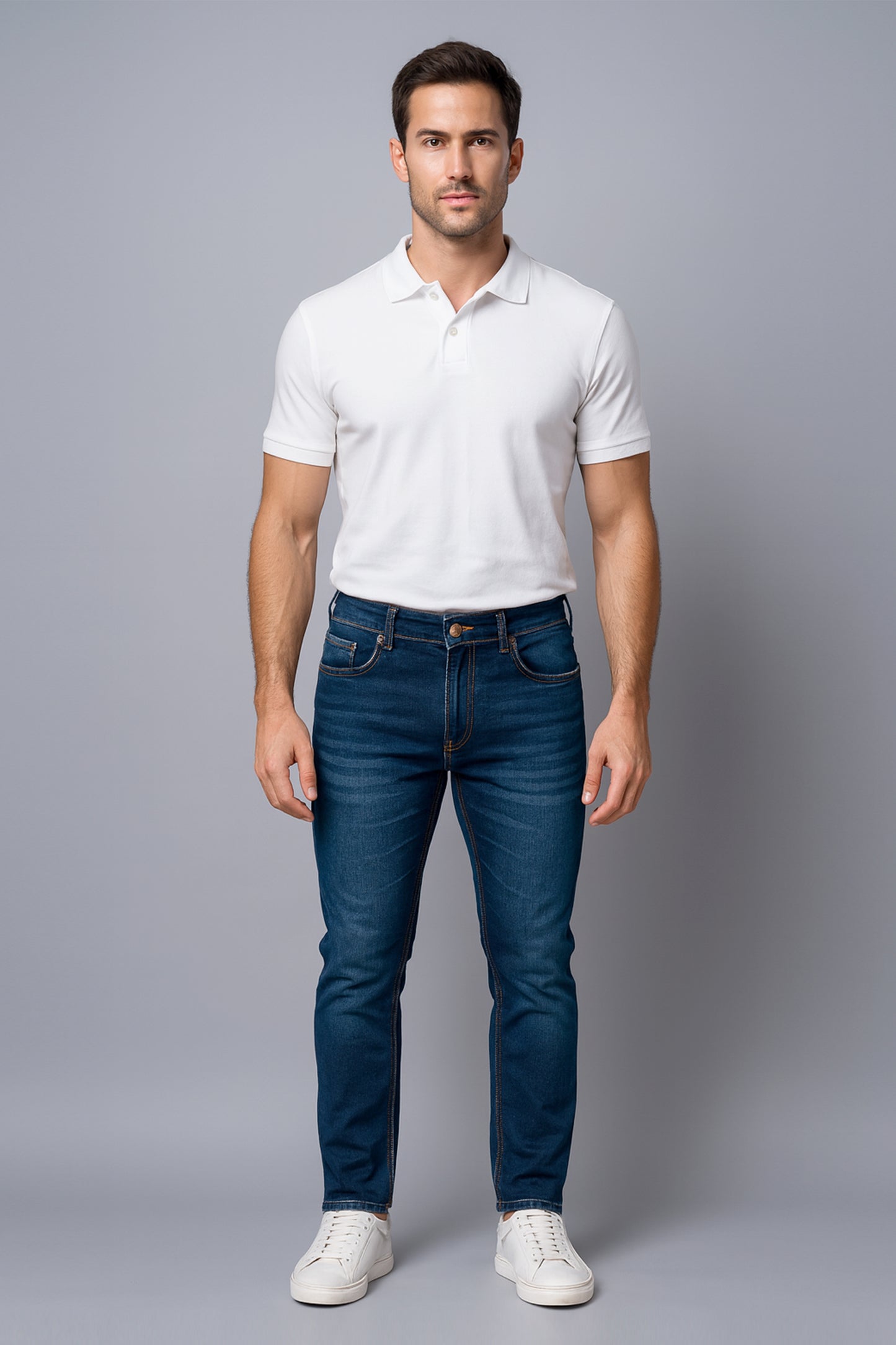 Man wearing a white polo shirt and blue jeans on a gray background