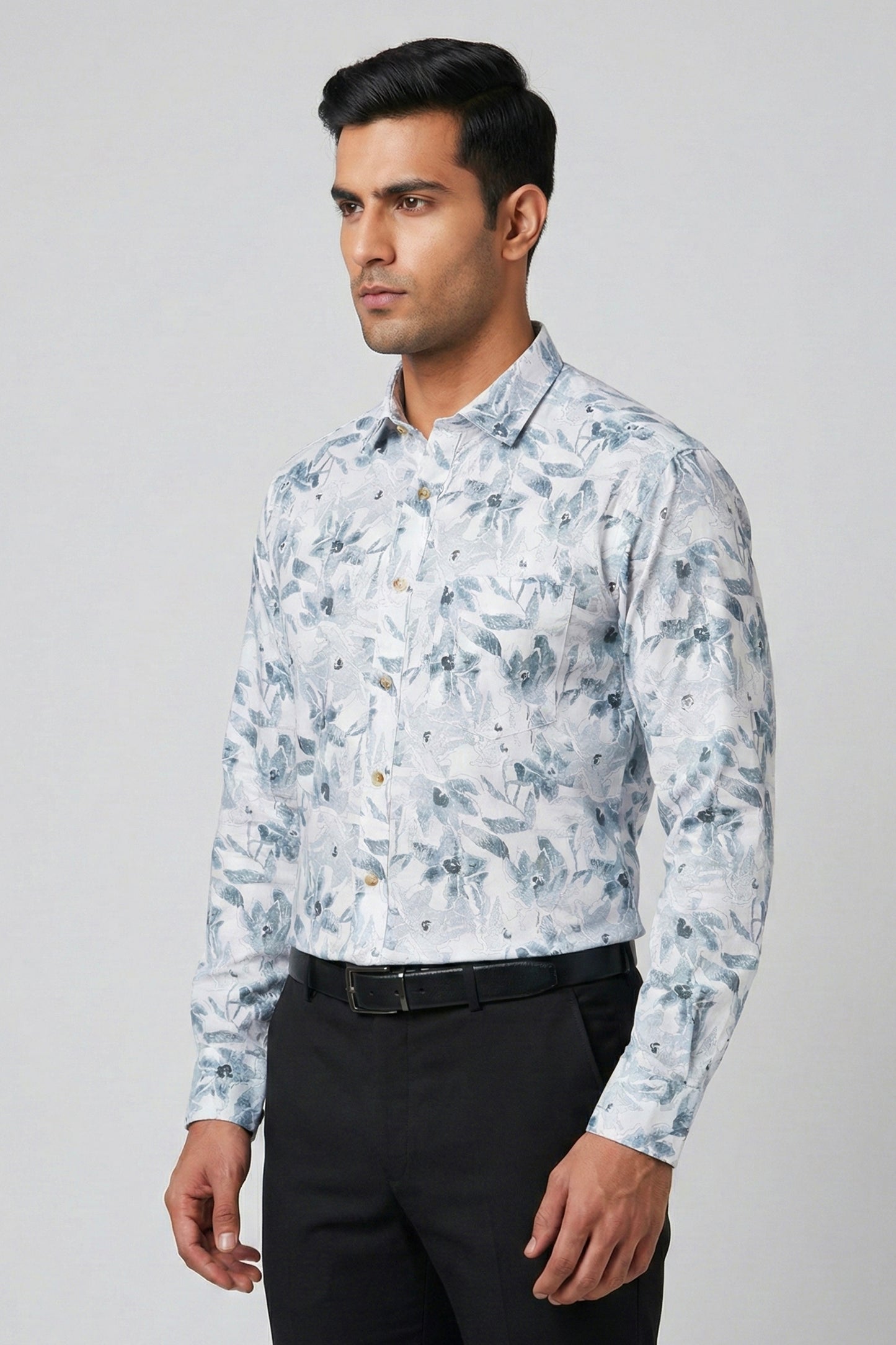 Man wearing a floral patterned shirt with black pants on a gray background