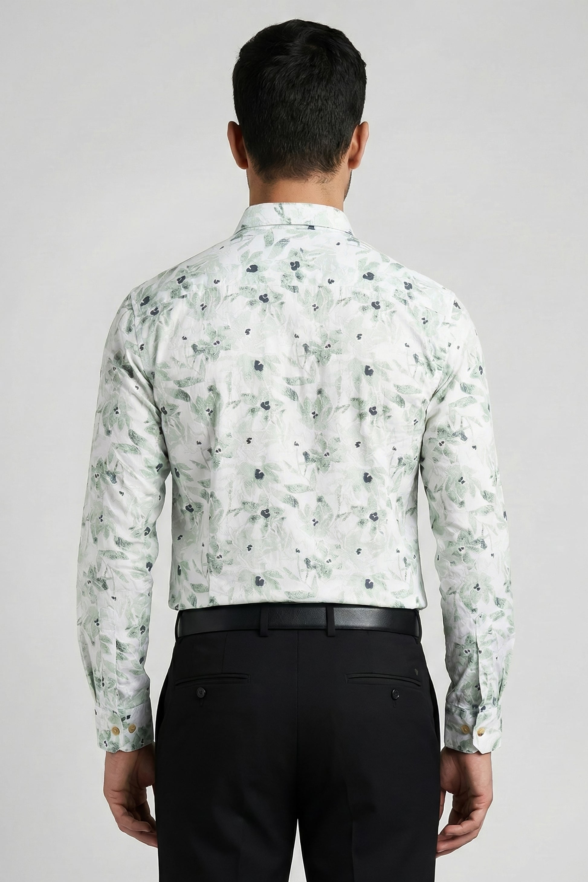 Man wearing a floral shirt and black pants on a plain background