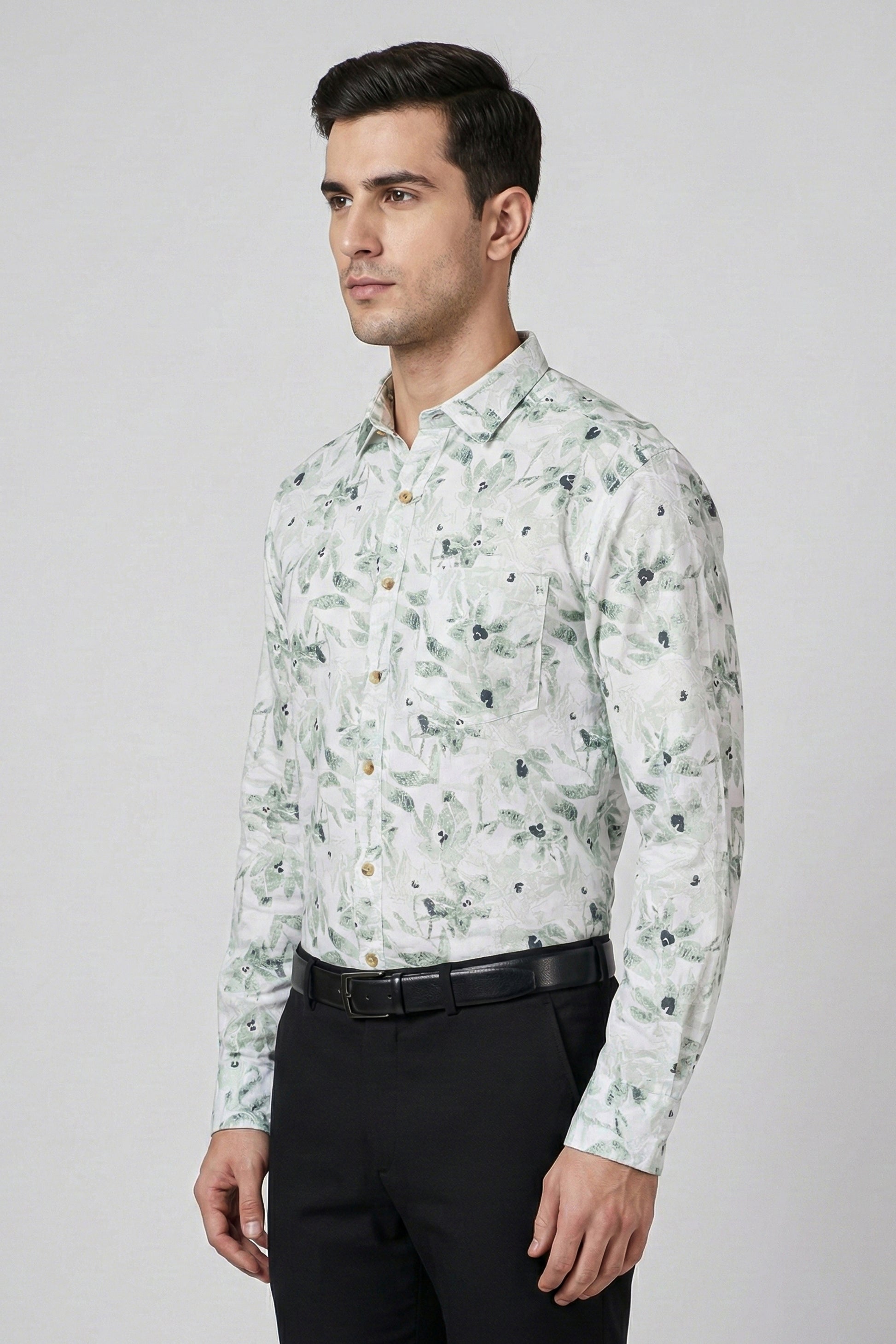 Man wearing a floral patterned shirt with black pants on a gray background