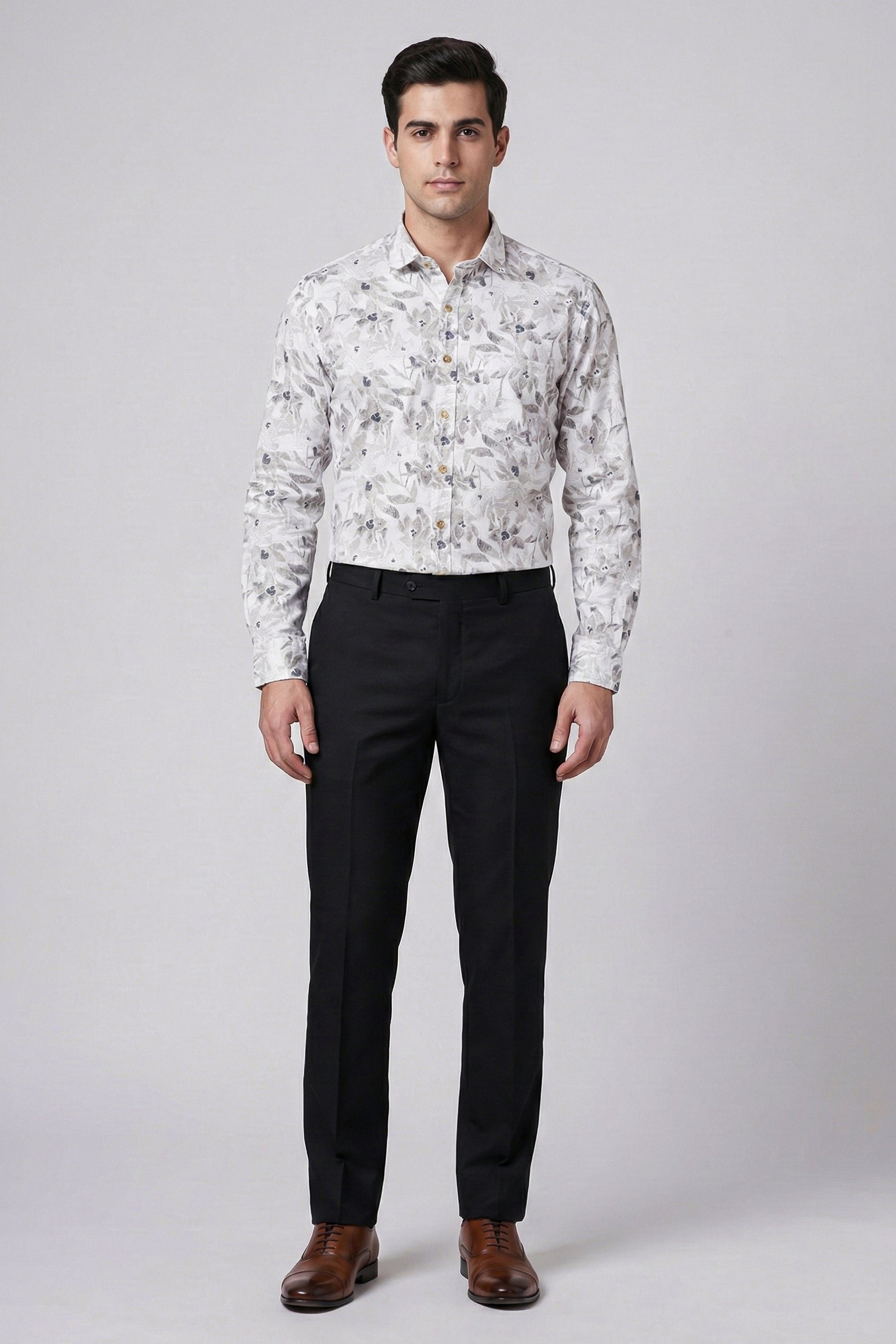 Man wearing a floral shirt and black pants on a gray background
