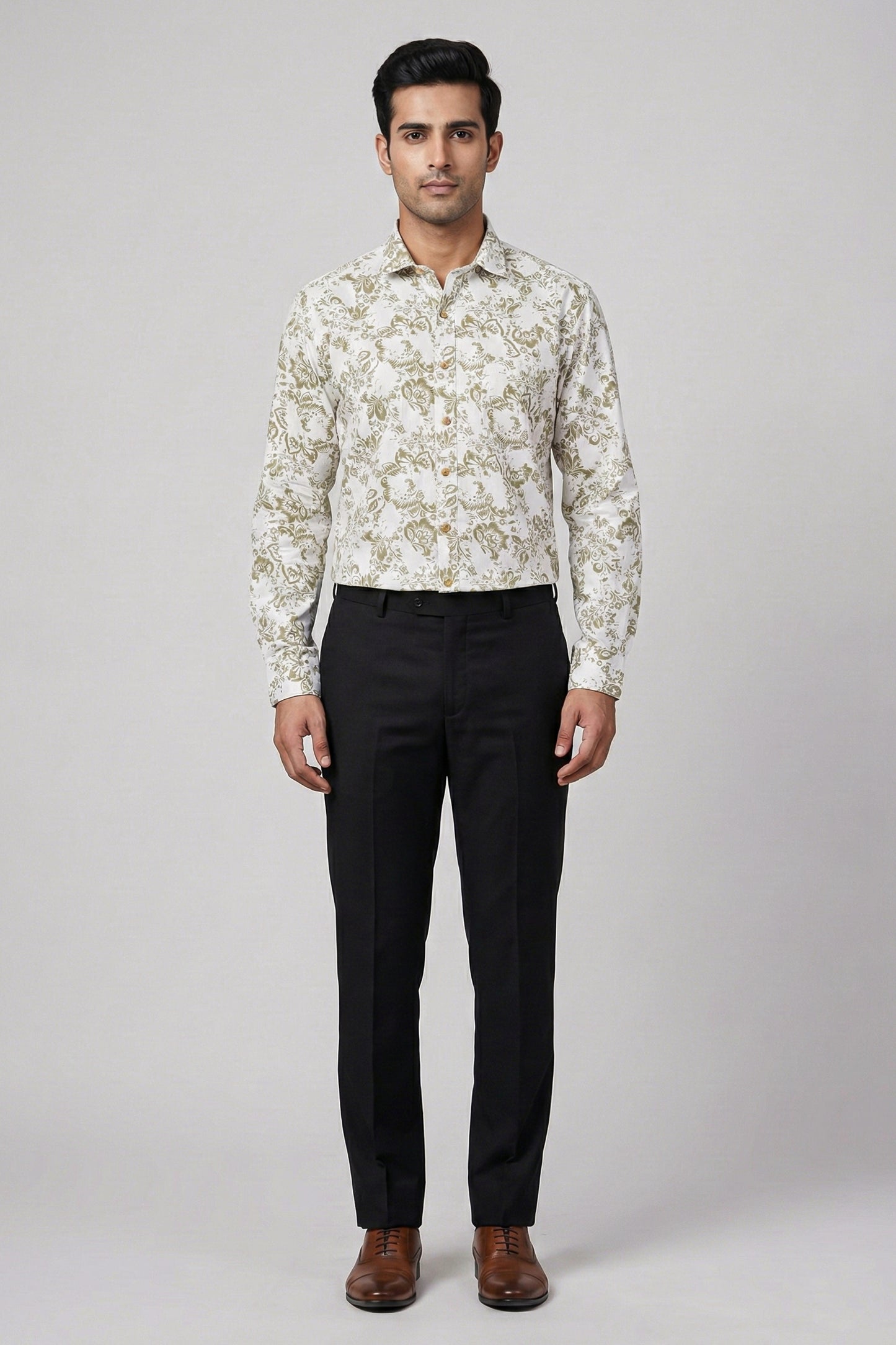 Man wearing a patterned shirt and black pants on a white background