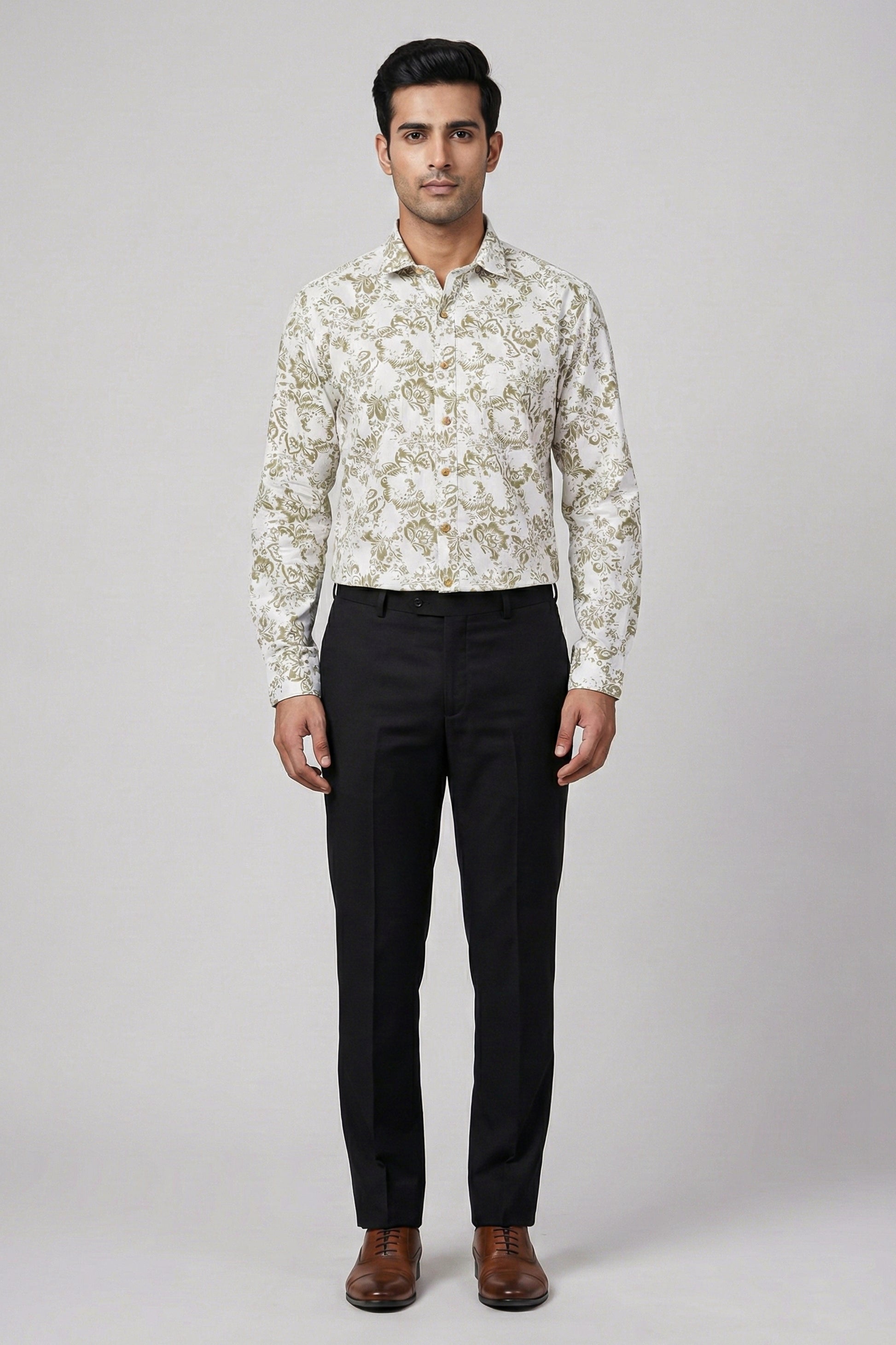 Man wearing a patterned shirt and black pants on a white background