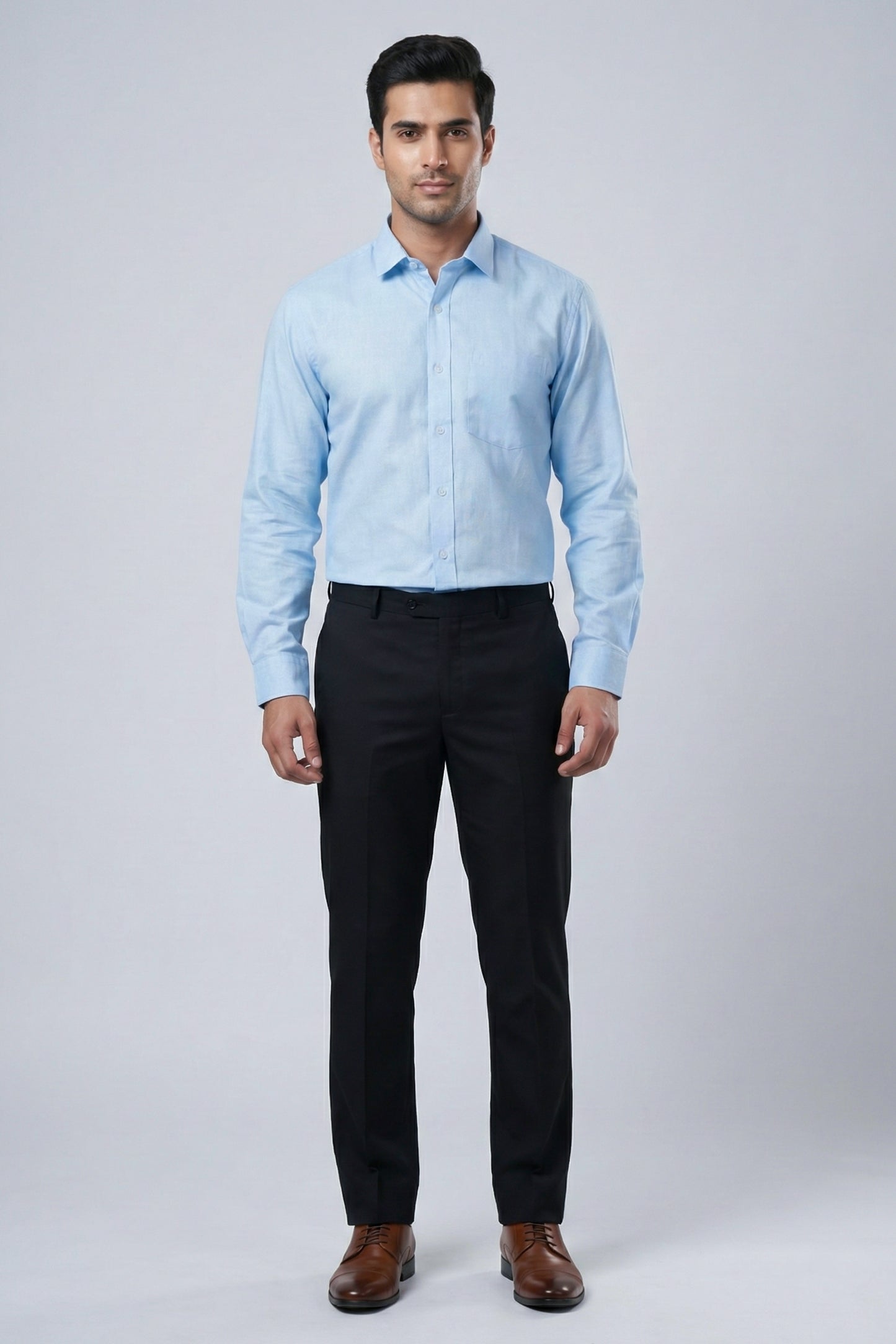 Man wearing a light blue checkered shirt and black pants on a white background