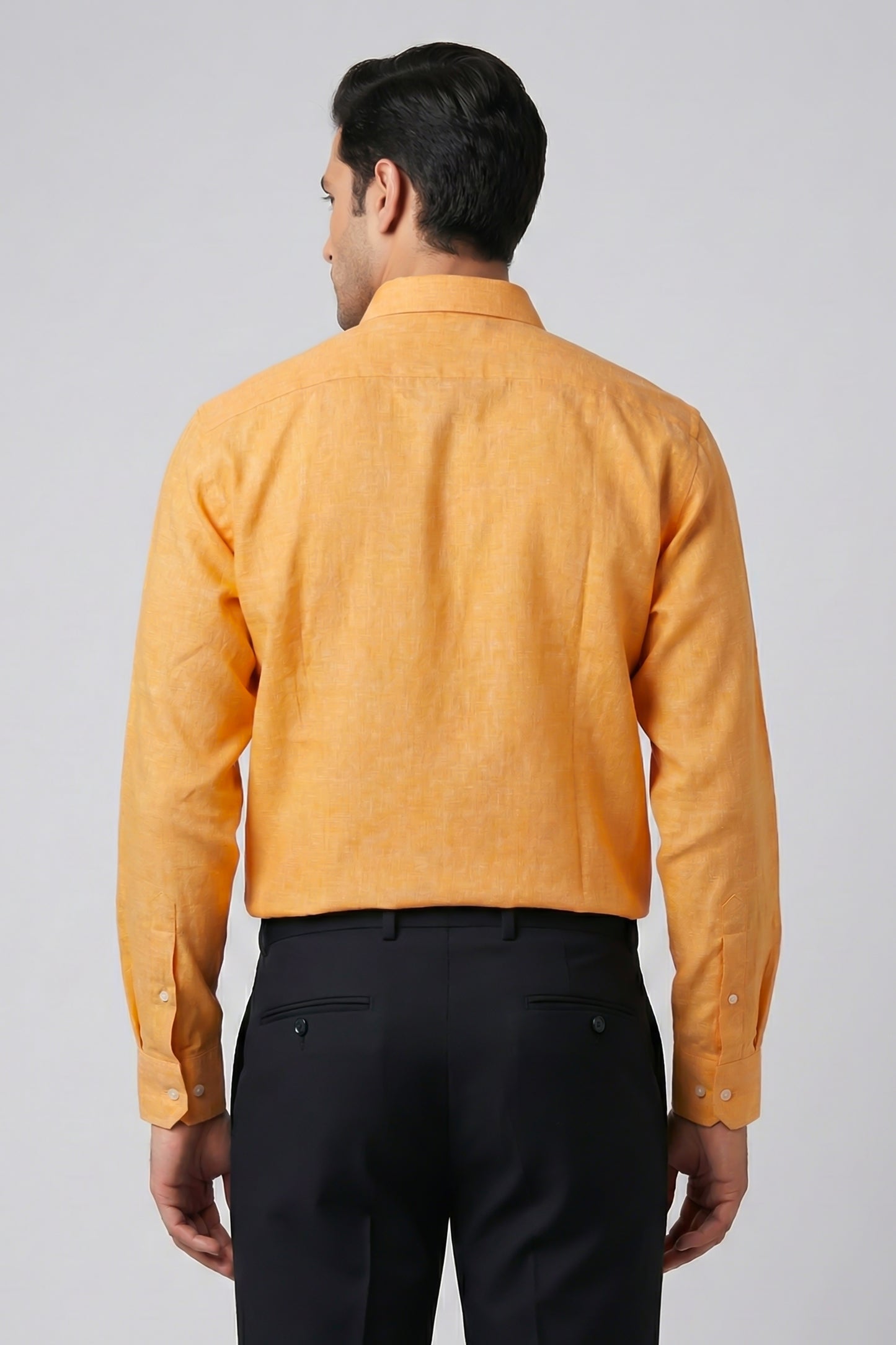 Man wearing a mustard yellow shirt and black pants on a gray background